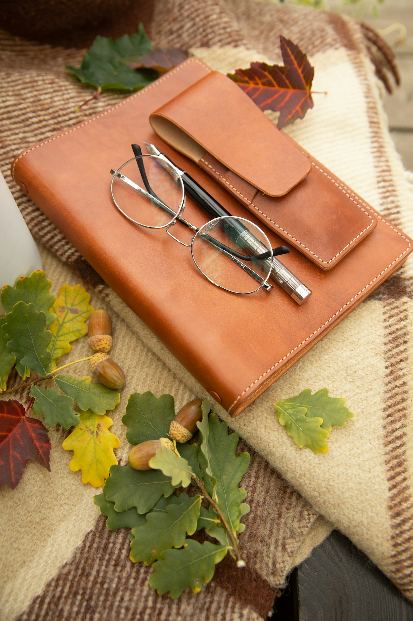 autumn still life notebook in a leather cover with glasses and a pen